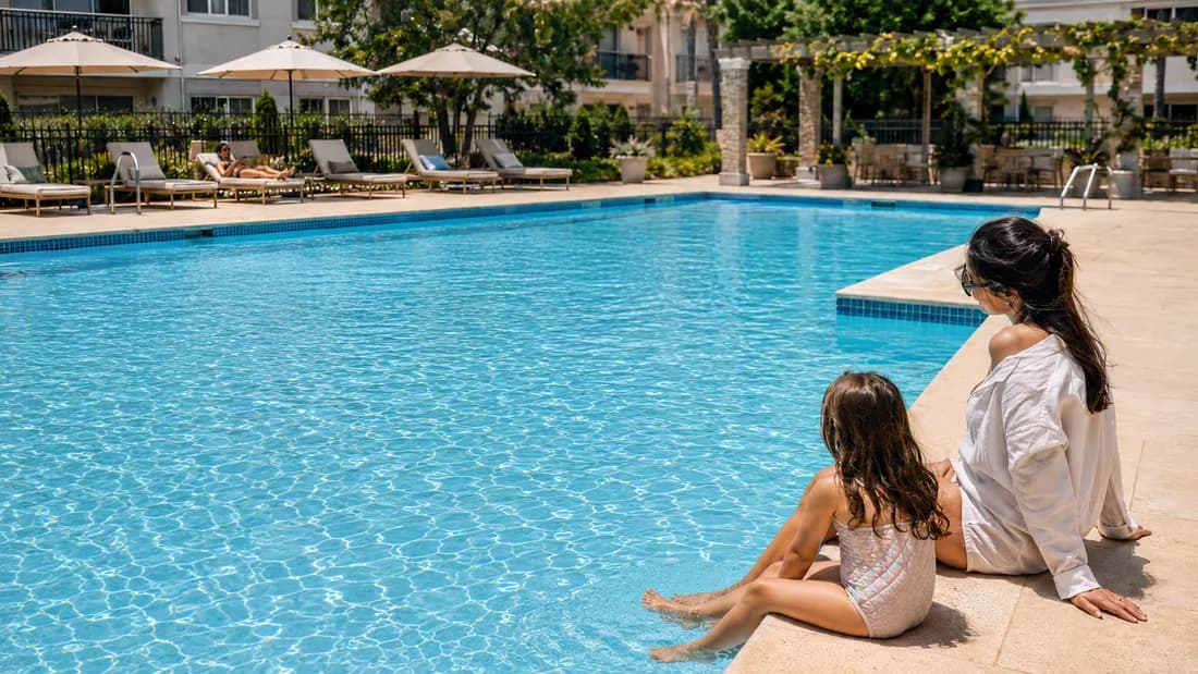 A mother and daughter relaxing at the edge of a pristine resort community pool