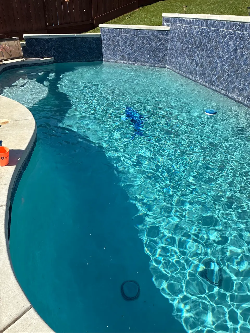 Sparkling turquoise pool water reveals submerged steps beneath raised blue tile walls and curved stone coping, after pool service in Antelope, CA
