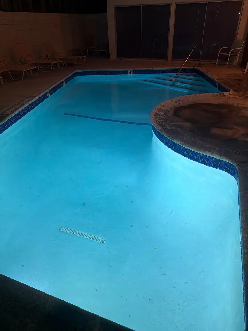 Clear blue water illuminates a curved pool with blue tile, entry steps, and visible floor marks, after pool service in Hermosa Beach, CA