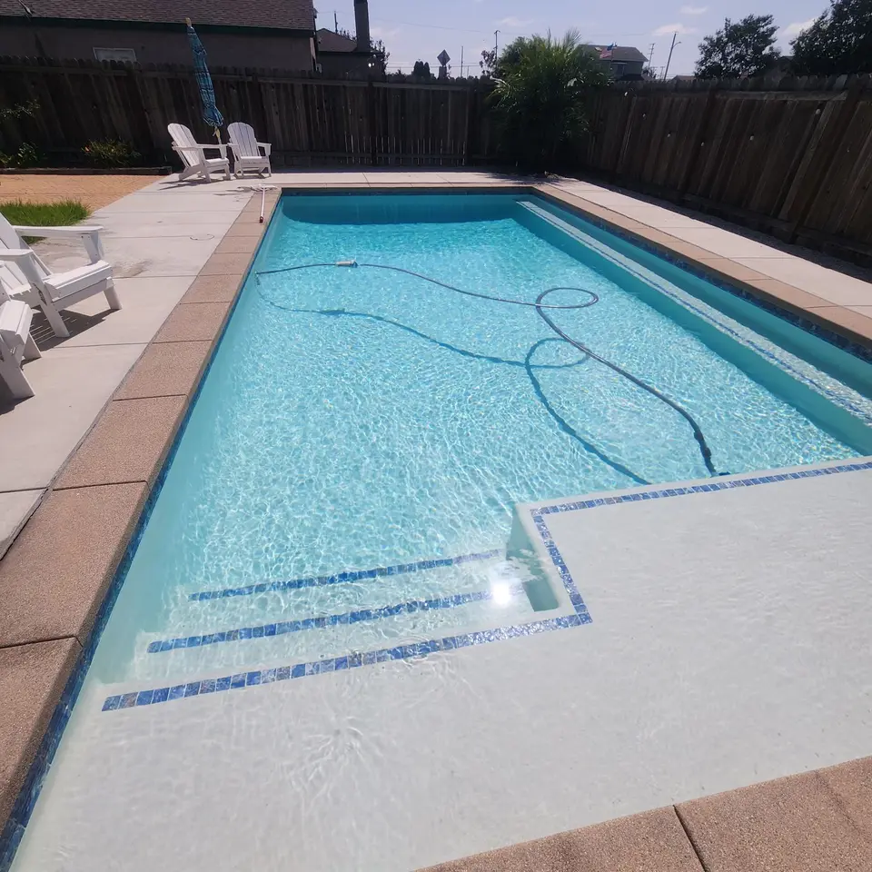 Sparkling blue water fills a rectangular pool with tiled entry steps, a shallow shelf, and a long underwater bench, after pool service in Inglewood, CA
