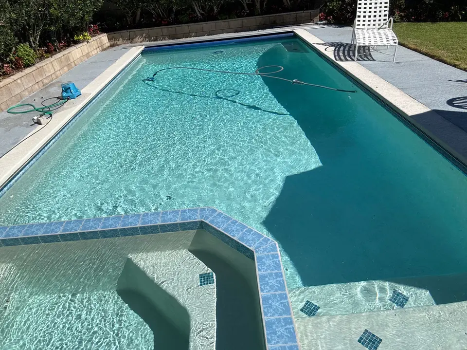 Sparkling turquoise pool with a raised tiled spa, submerged entry steps, and landscaped borders, after pool service in Manhattan Beach, CA