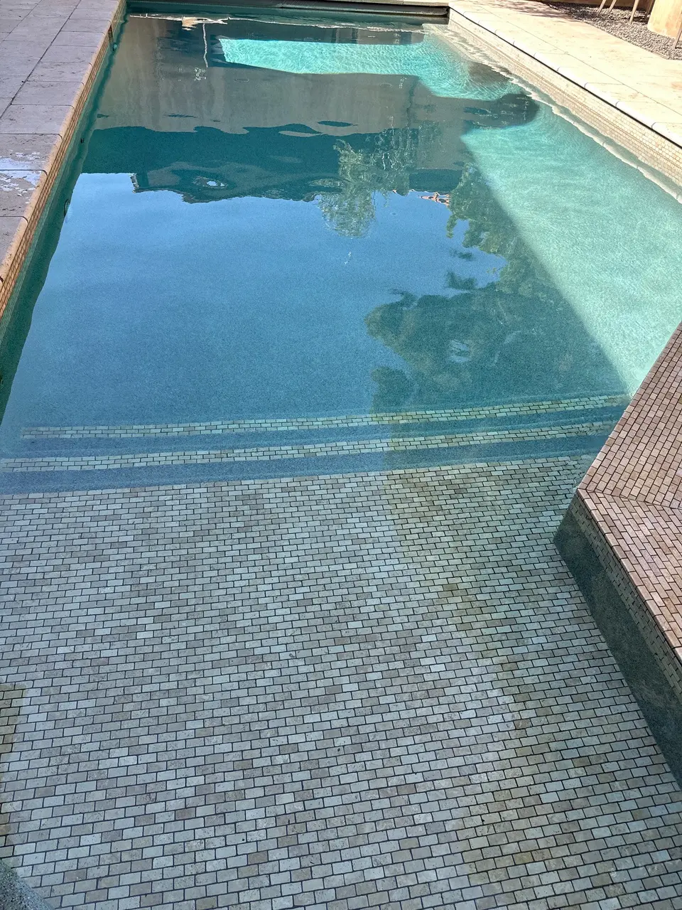 Clear blue water reveals a tiled shallow entry and wide steps in a rectangular pool, after pool service in Manhattan Beach, CA