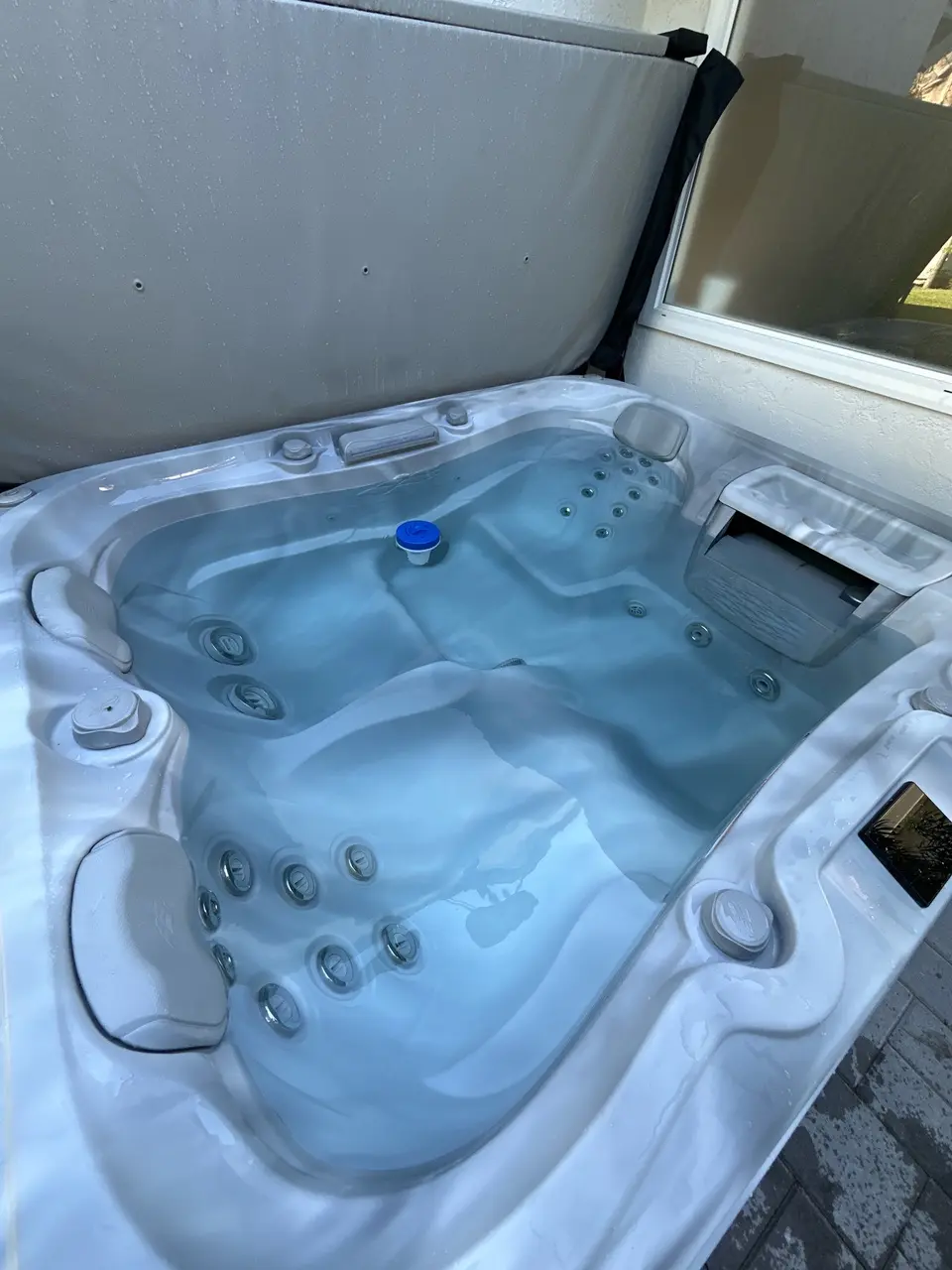 Clear water fills a light-colored spa with molded seating, multiple jets, headrests, and a floating dispenser, after pool service in Rancho Santa Fe, CA