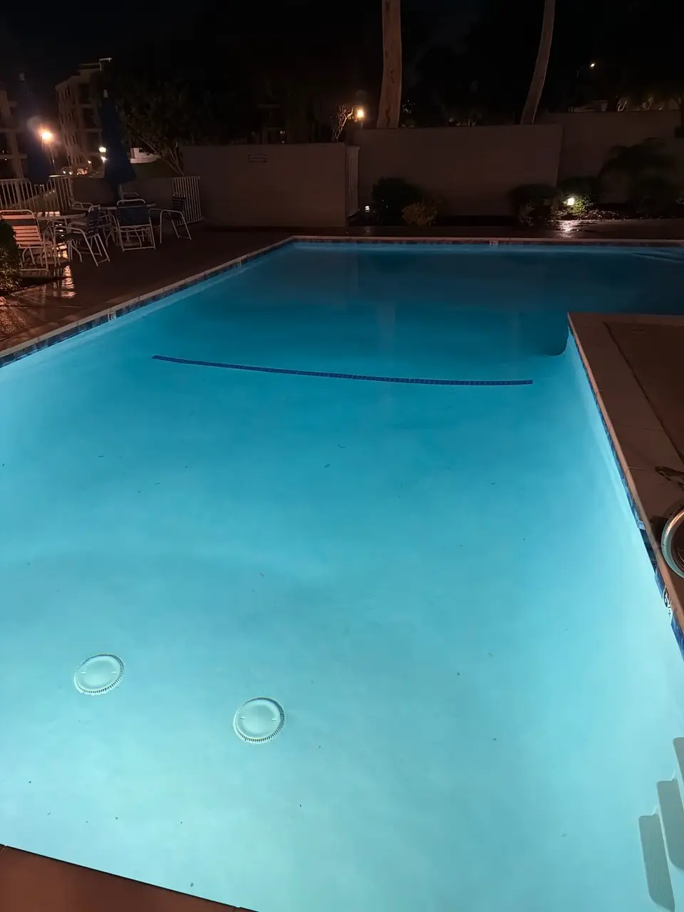 Clear blue pool water glows under underwater lighting, with entry steps, waterline tile, and poolside seating, after pool service in Redondo Beach, CA