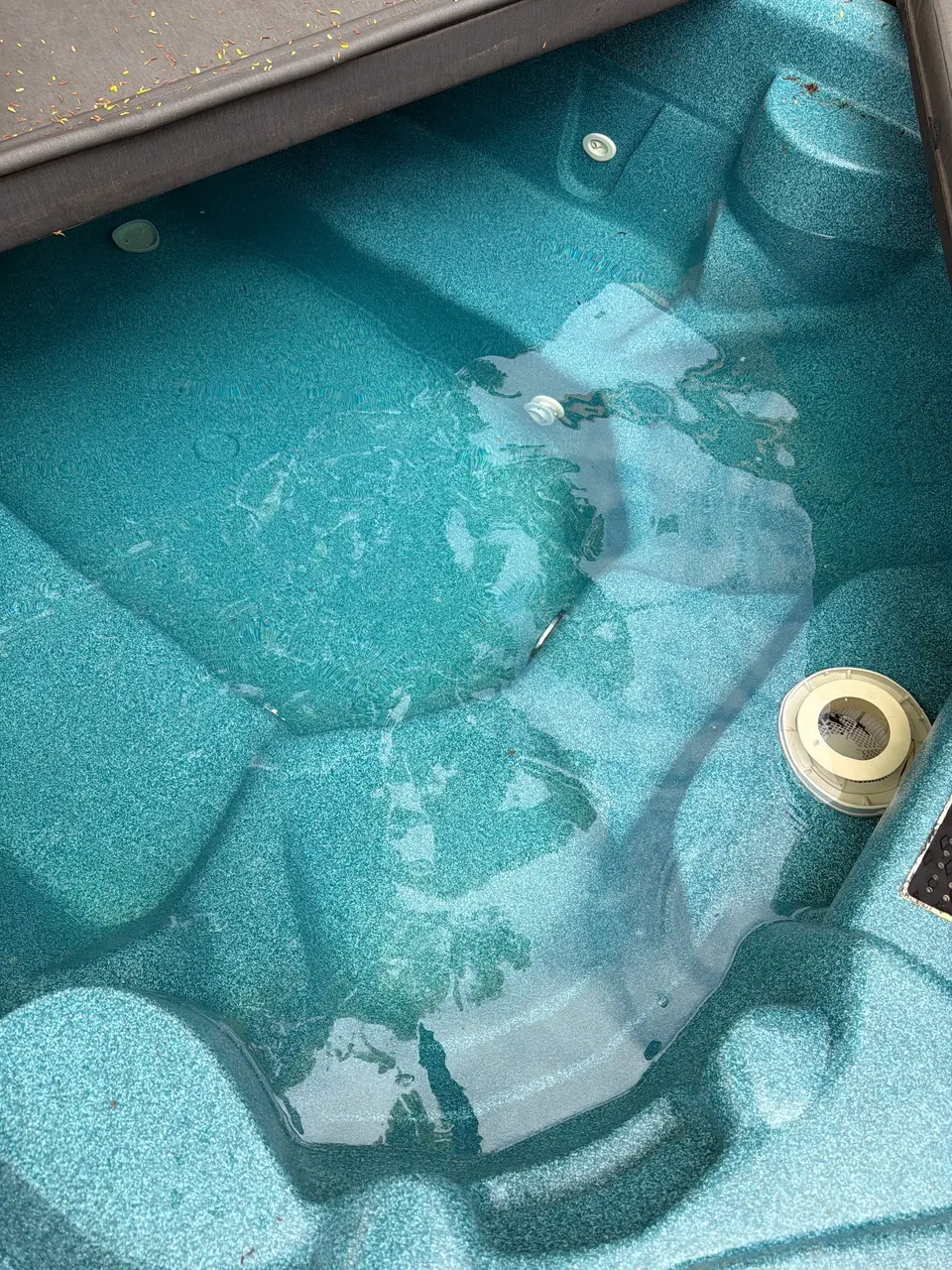 Clear water reveals molded seating and jets in a turquoise spa with a floating chemical dispenser, after pool service in San Diego, CA