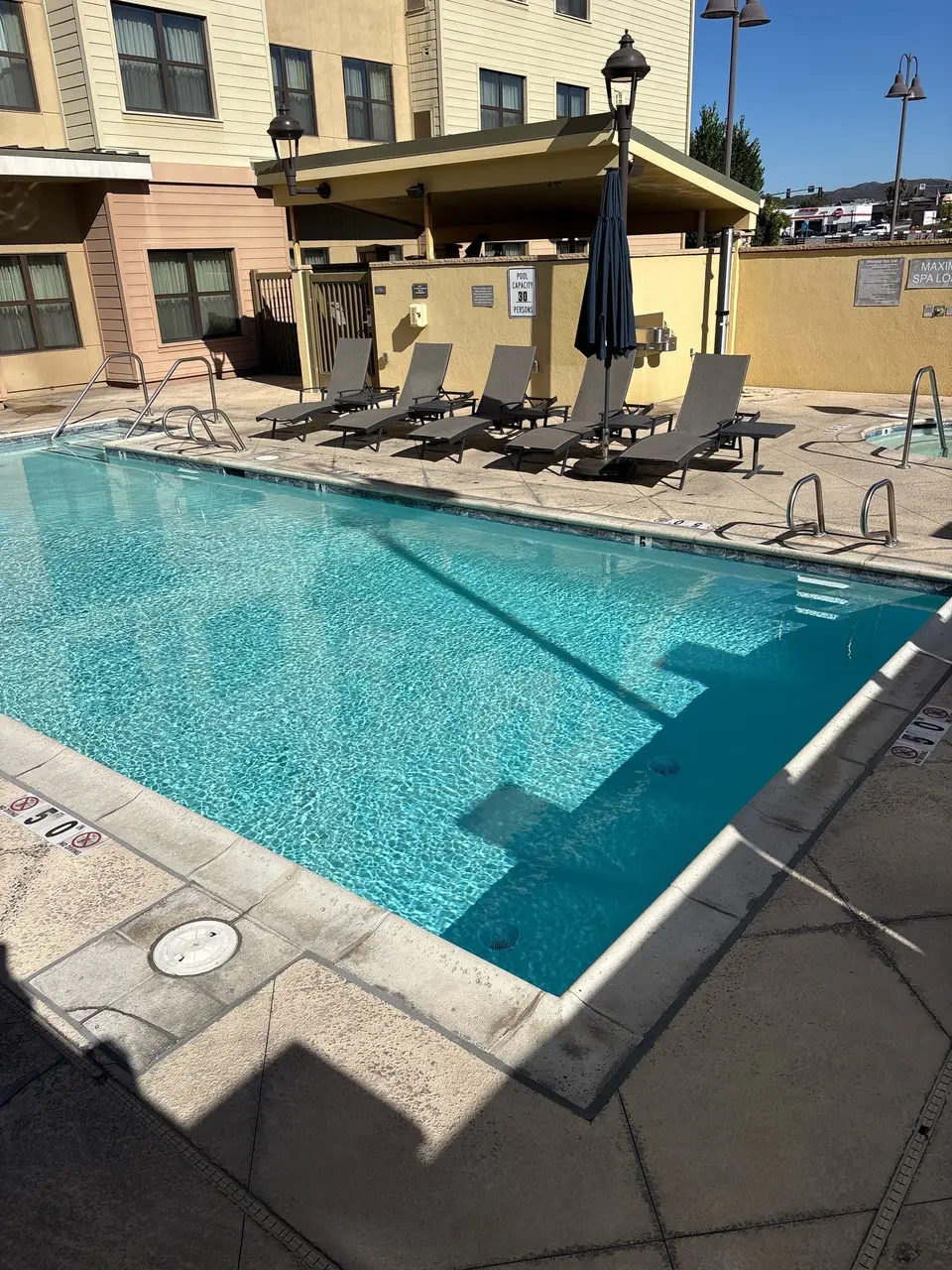 Sparkling turquoise pool water with stainless steel handrails, poolside loungers, and a partially visible adjacent spa, after diagnosis visit in San Marcos, CA