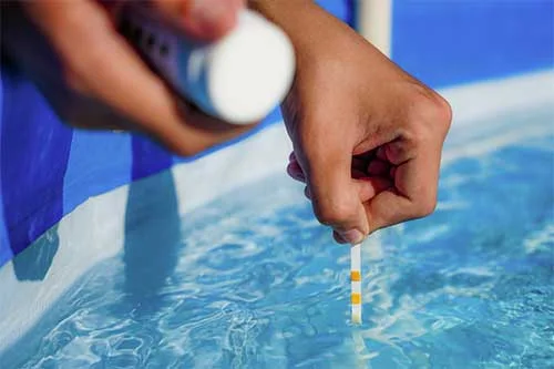 Technician testing pool water chemistry using test strips